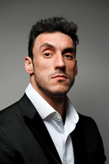 Close up portrait of a man 30-34 years old in a white shirt and a black jacket on a gray background. 