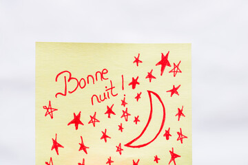 Bonne nuit (good night) handwriting text close up isolated on yellow paper with copy space.