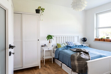 Scandinavian design with white bedroom and wooden furniture. Stylish and cozy interior with bed ,window and white wall with copy space.