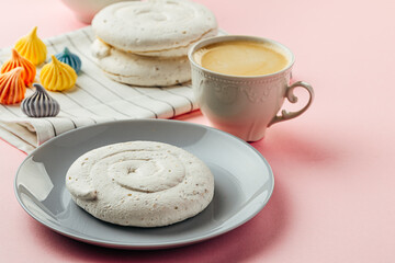 White meringue cookie on pink background with colorful mini meringues