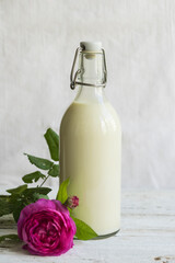 Ayurvedic rose milk or matcha drink. On a wooden white table is a bottle of milk with a pink rose