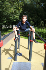 Fototapeta premium Child trains abdominal muscles on uneven bars