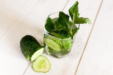 Infused water with cucumber, lime and mint on wood background. Cucumber lemonade