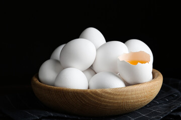 Many fresh raw chicken eggs in bowl on table