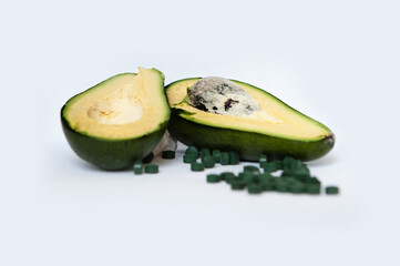 Slices of avocado on white background with green pills