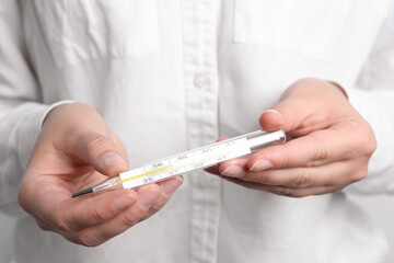 Closeup view of woman holding mercury thermometer