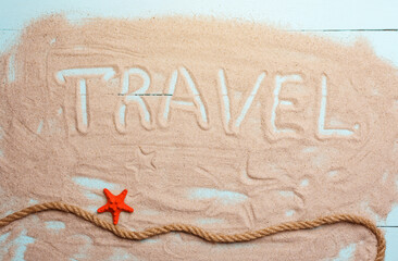 Inscription travel on the sand. Starfish and rope on summer background.