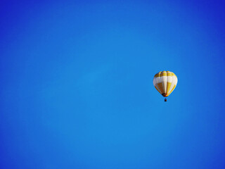 balloon flying mid-air in sunshine against blue sky