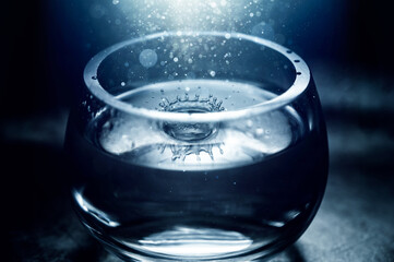 water drop in glass bowl with sparkling light from above