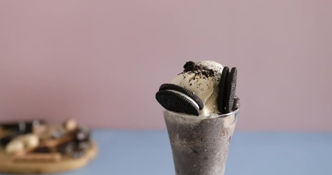 Decorating parfait with Oreo cookies and ice cream and biscuits