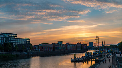 Fototapeta premium Sunset in summer landscape view blue orange sky in Europe Bremen Germany tourism landmark sightseeing in Schlachte weser river with old vintage boat ship medieval