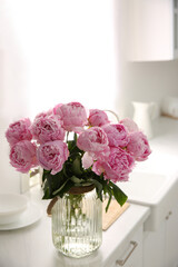 Vase with bouquet of beautiful pink peonies in kitchen