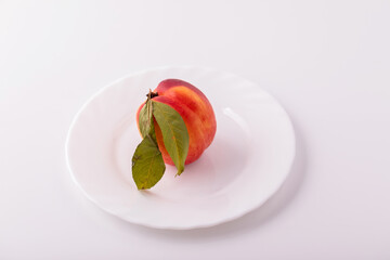 Nectarine peaches with a slice and leaves on a white background