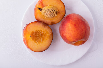 Nectarine peaches with a slice and leaves on a white background