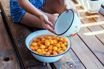 girl washes yellow fruits with her hands in a bowl of water. healthy eating, traditional lifestyle