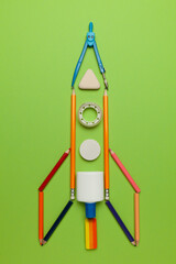 Spaceship (rocket) from stationery on green background. Child imagination, science in elementary school. (preschool)