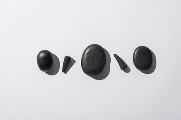 top view of black incense cones and spa stones on white background