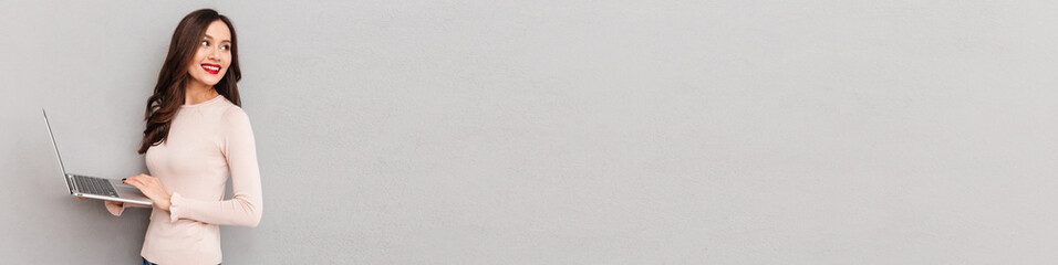 Fototapeta premium Half-turn image of cute female in casual clothes working on notebook