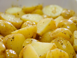 Macro close-up of sliced potatoes seasoned with herbs and olive oil