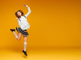 Fototapeta na wymiar Full length portrait of an excited teenage schoolgirl in uniform