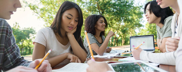 Multiethnic group of young students sitting and studying