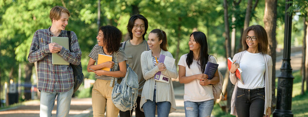 Multiethnic group of young cheerful students walking