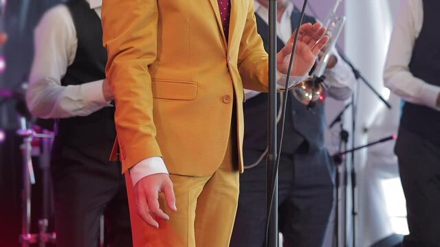 Handsome singer in mustard suit sings a song at music stage