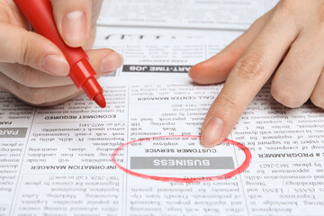Obraz premium Woman marking advertisement in newspaper, closeup. Job search concept