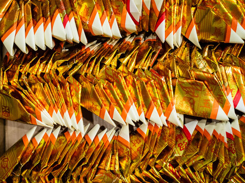 Gold Chinese joss paper folded into the shape of a gold ingot for ancestral  worship or prayer Stock Photo