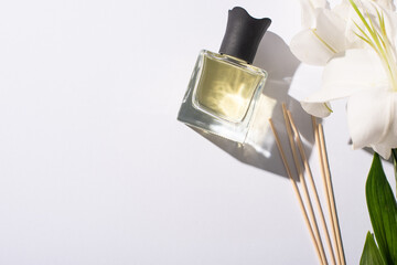 top view of aroma sticks with perfume in bottle near lilies on white background