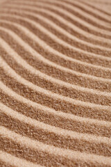 Wavy pattern on a beach in the summer. The textured surface of sand on the beach after a strong wind in the form of waves close up.