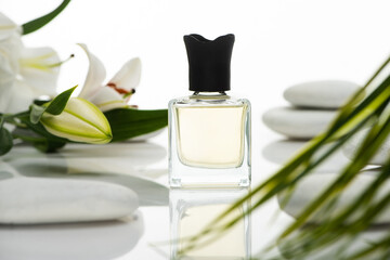 selective focus of perfume near spa stones and lilies isolated on white