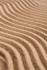 Wavy pattern on a beach in the summer. The textured surface of sand on the beach after a strong wind in the form of waves close up.