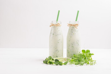Green smoothie milkshake with the addition of fresh microgreen grass sprouts bottles white background .