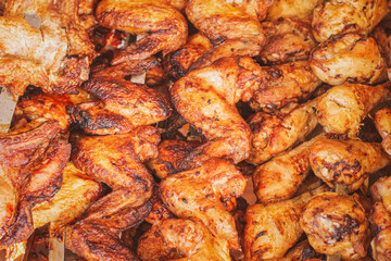 Chicken wings and drumstick fried on a charcoal grill until golden crust. Chicken on skewers with selective focus. Poultry meat roasted on coals at a street market counter.