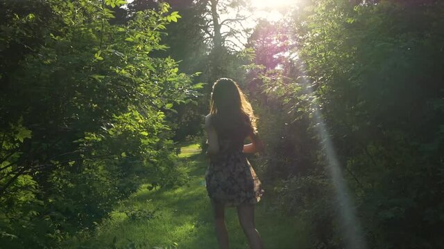 Beautiful Woman Running in Green Lush Forest with Sunset
