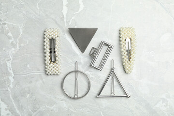 Stylish hair clips on grey marble table, flat lay