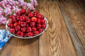 fresh, juicy cherries in a plate on a wooden table close-up, rustic style