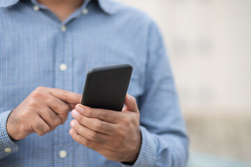Close up male hands holding using black smartphone on city background.