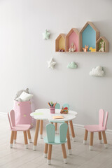 House shaped shelves and little table with chairs in children's room. Interior design