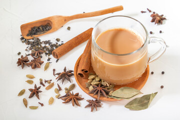 Masala tea in a glass cup and a natural mixture for its preparation - star anise, cinnamon sticks,...