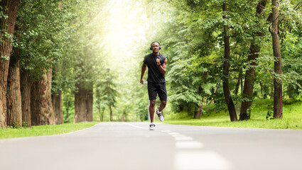 Motivated african sportsman jogging at city park