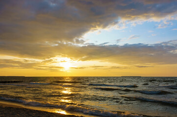 Sunset over the sea. Reflection of sunlight in the sea waves. The sky in the sunset rays.