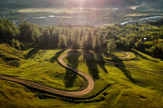 Beautiful curvy country road with fir trees in background during the sunrise with rays of light. Comanesti, Romania.