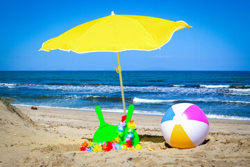 Fototapeta na wymiar Beach ball, rackets and parasol by the sea