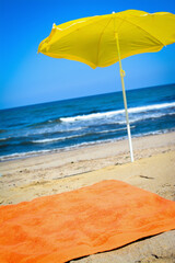 Orange towel and yellow parasol on the beach