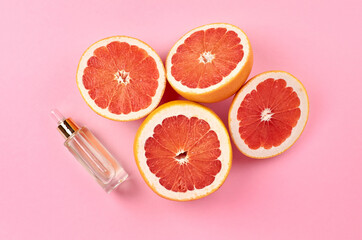 Grapefruit pure essential oil with fresh grapefruit halves on pink background
