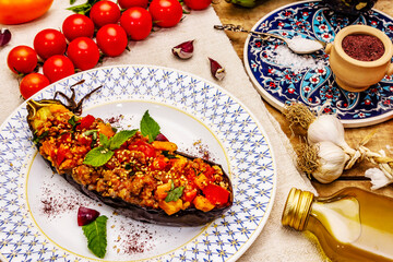 Karniyarik traditional Turkish food from stuffed eggplants with minced meat, tomato, greens and sesame seeds