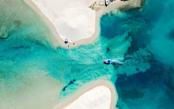 Aerial photo of white beach and blue sea lagoon with motor boat. Halkidiki peninsula, Greece. Summer background.