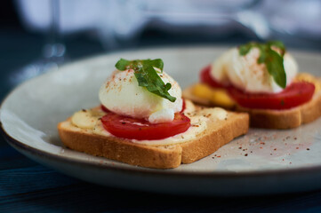 Fototapeta na wymiar Tasty home breakfast of square toast with sliced fresh tomato and egg benedict with urugula.
